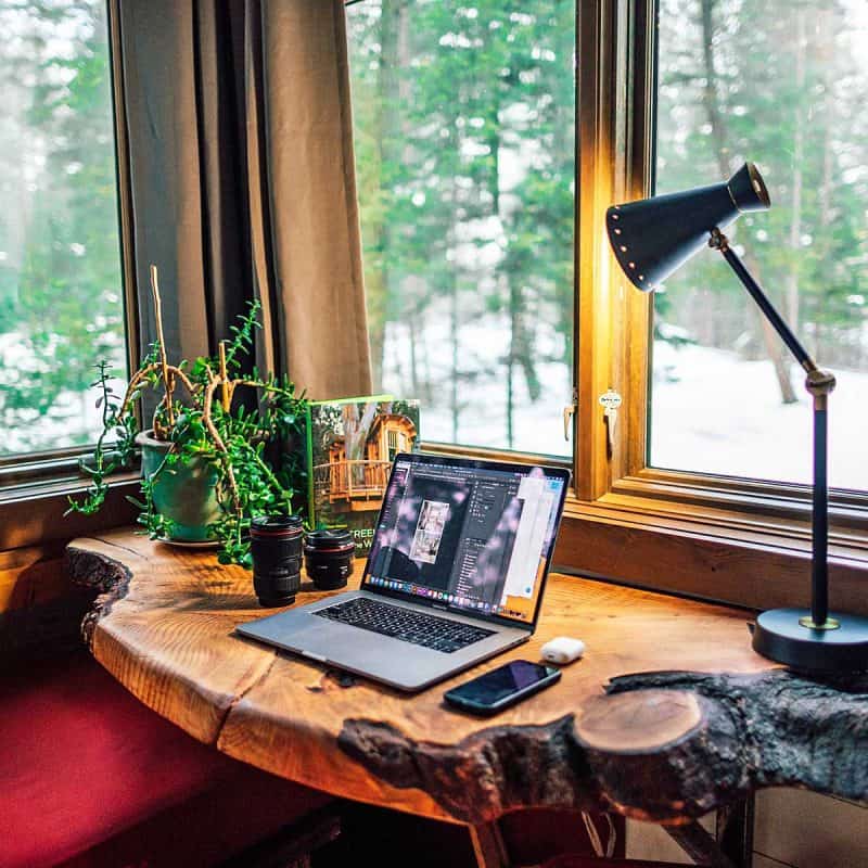 A live edge wood desk with a laptop and desk lamp.