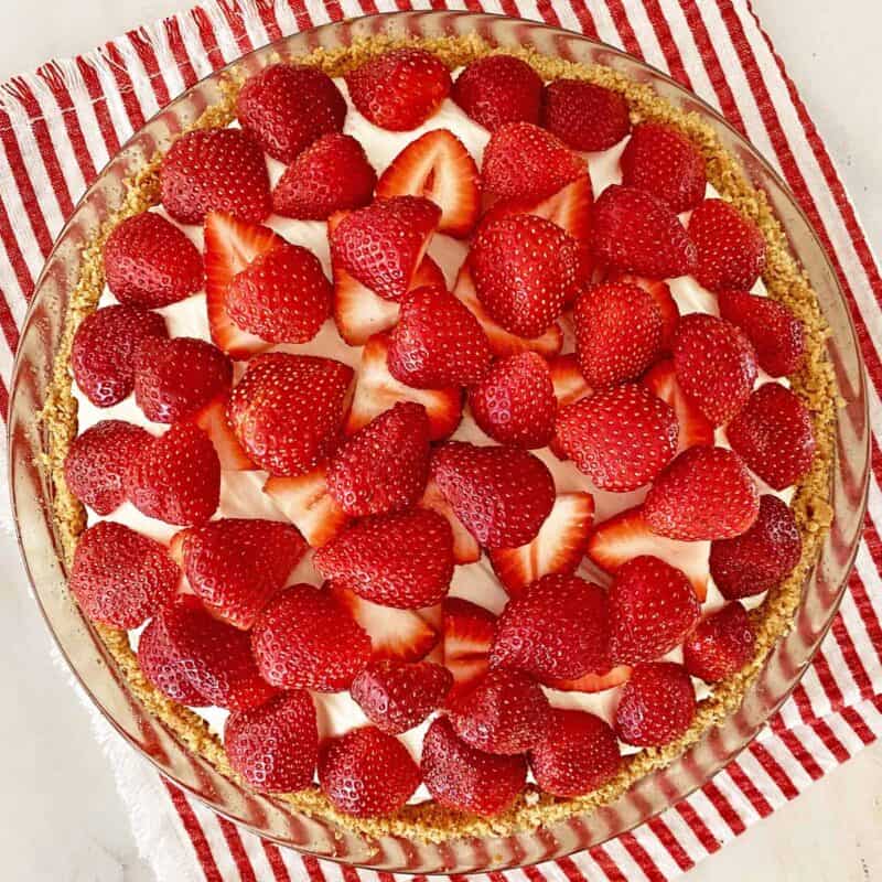 no bake cheesecake with strawberries on a red and white striped napkin.